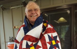 older man wrapped in quilt
